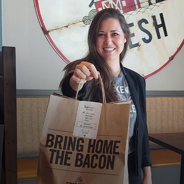 Angela Mitchell holds a to-go bag at one of the Virgina First Watch locations she oversees